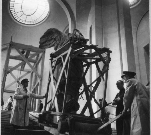 Photographie montrant trois personnes montant la statue Victoire de Samothrace en haut d'un escalier